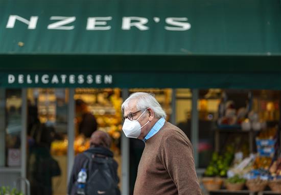 10月12日，一名男子戴着口罩从伦敦一家商店前走过。新华社 图